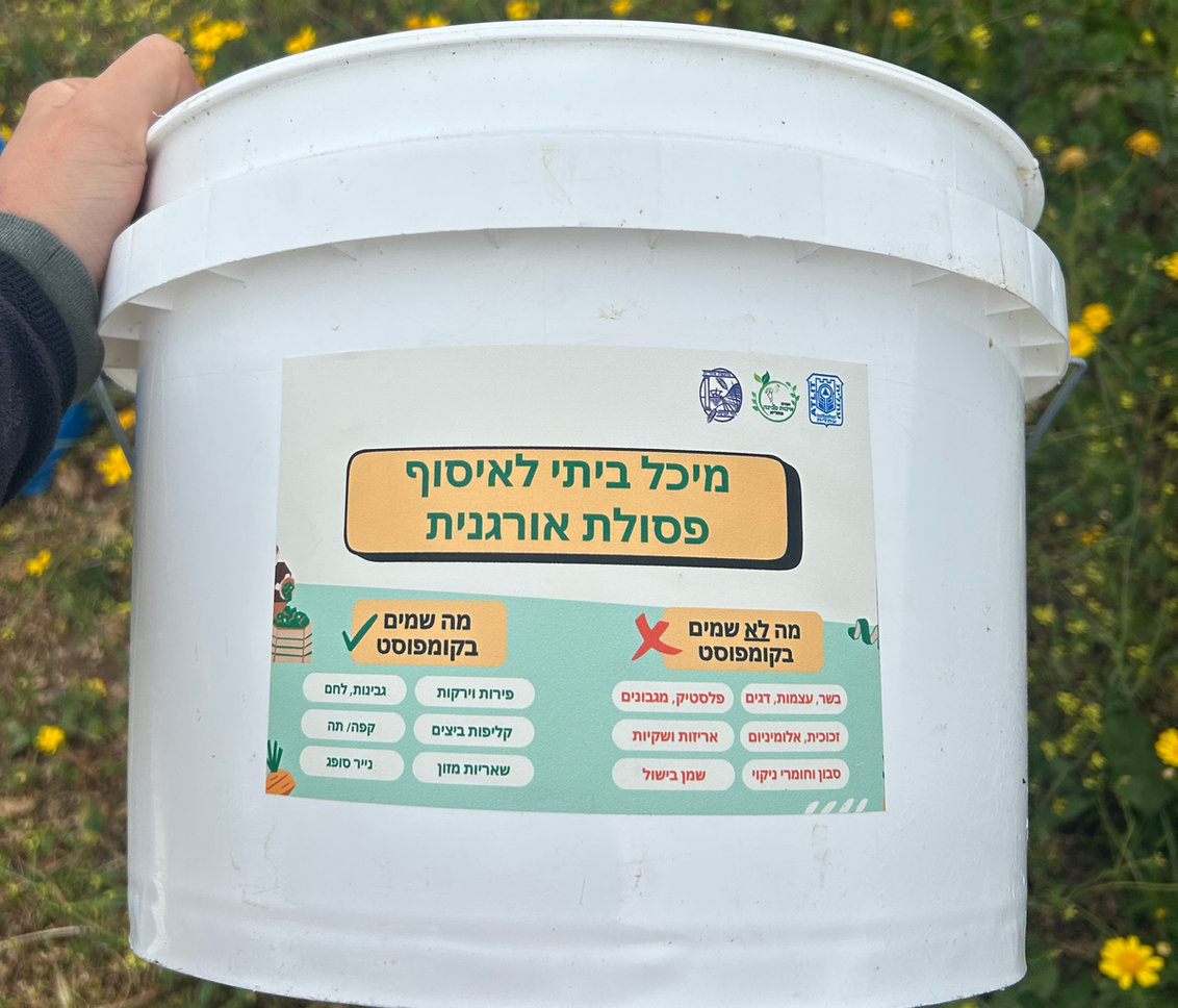 דלי איסוף פסולת אורגנית עבור קומפוסט קהילתי על רקע פריחה